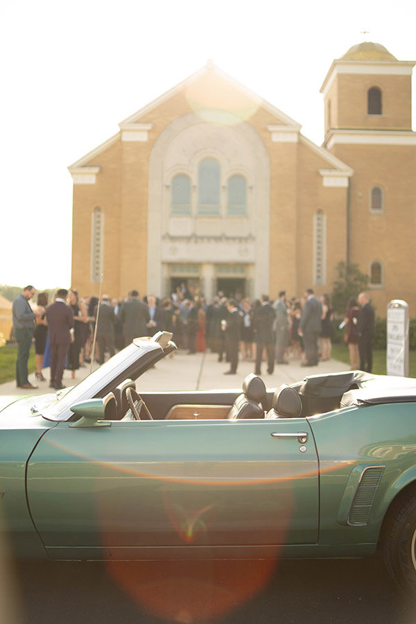 Detail of guests and classic car outside of church