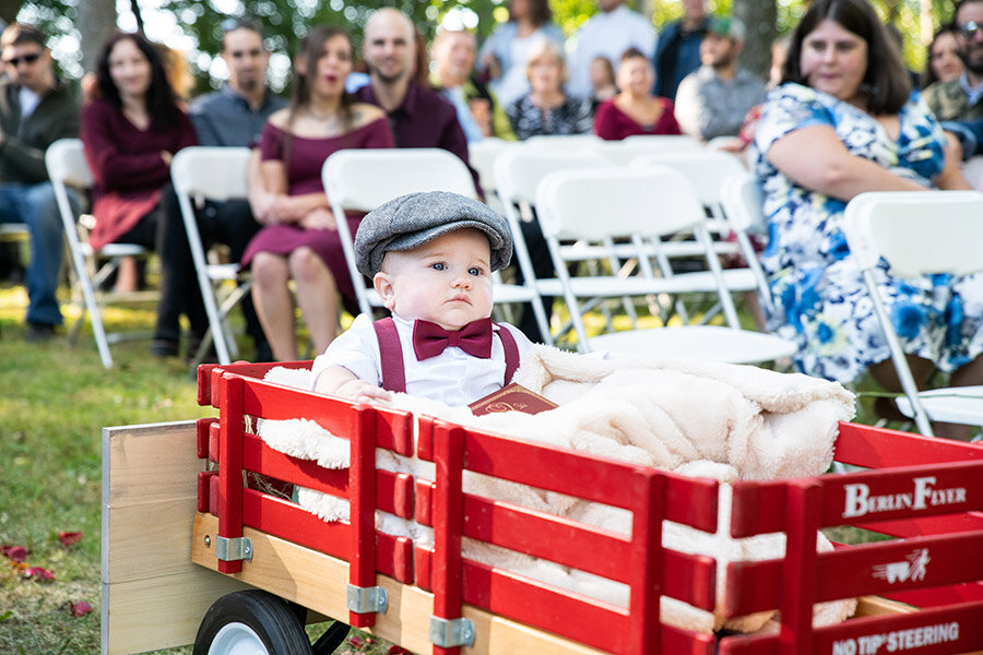 Ring bearer going down the aisle in a wagon