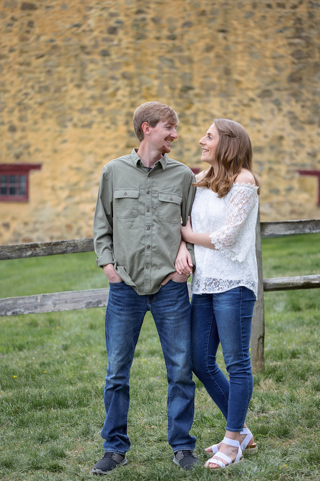 Couple looking at each other in front of a rustic yellow barn