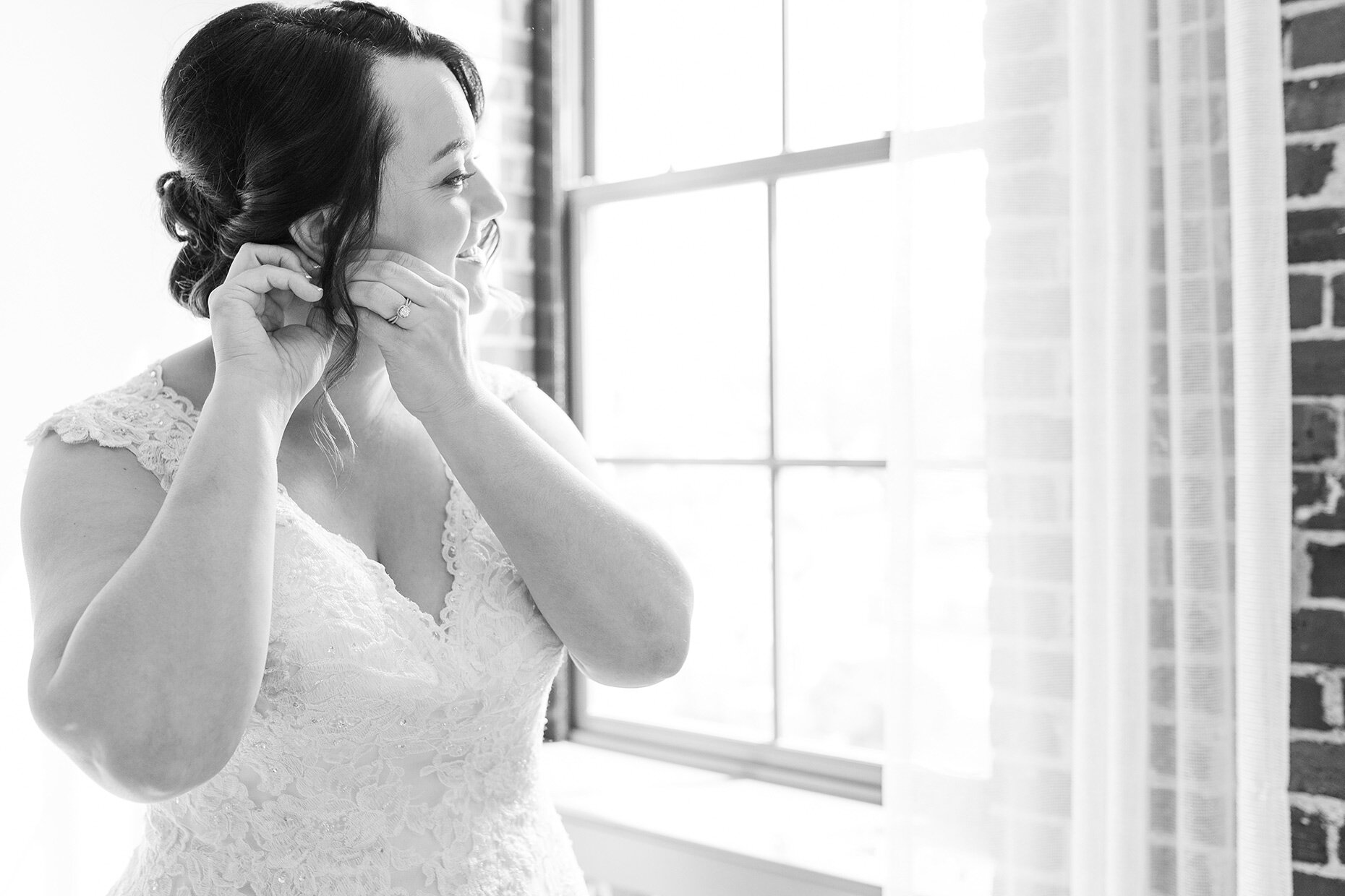 Bride getting ready by window in black and white