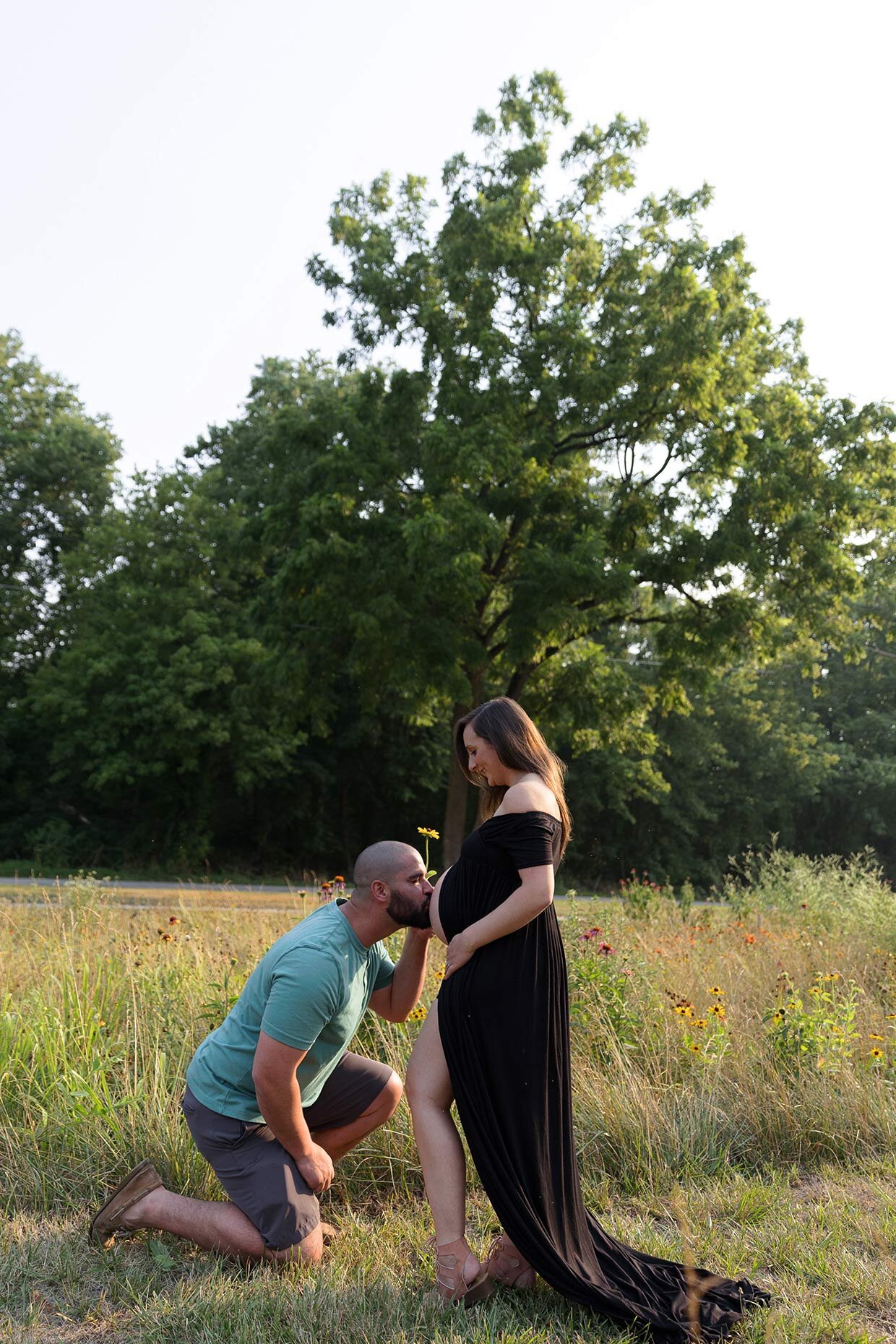 Kissing belly at maternity shoot with a daisy
