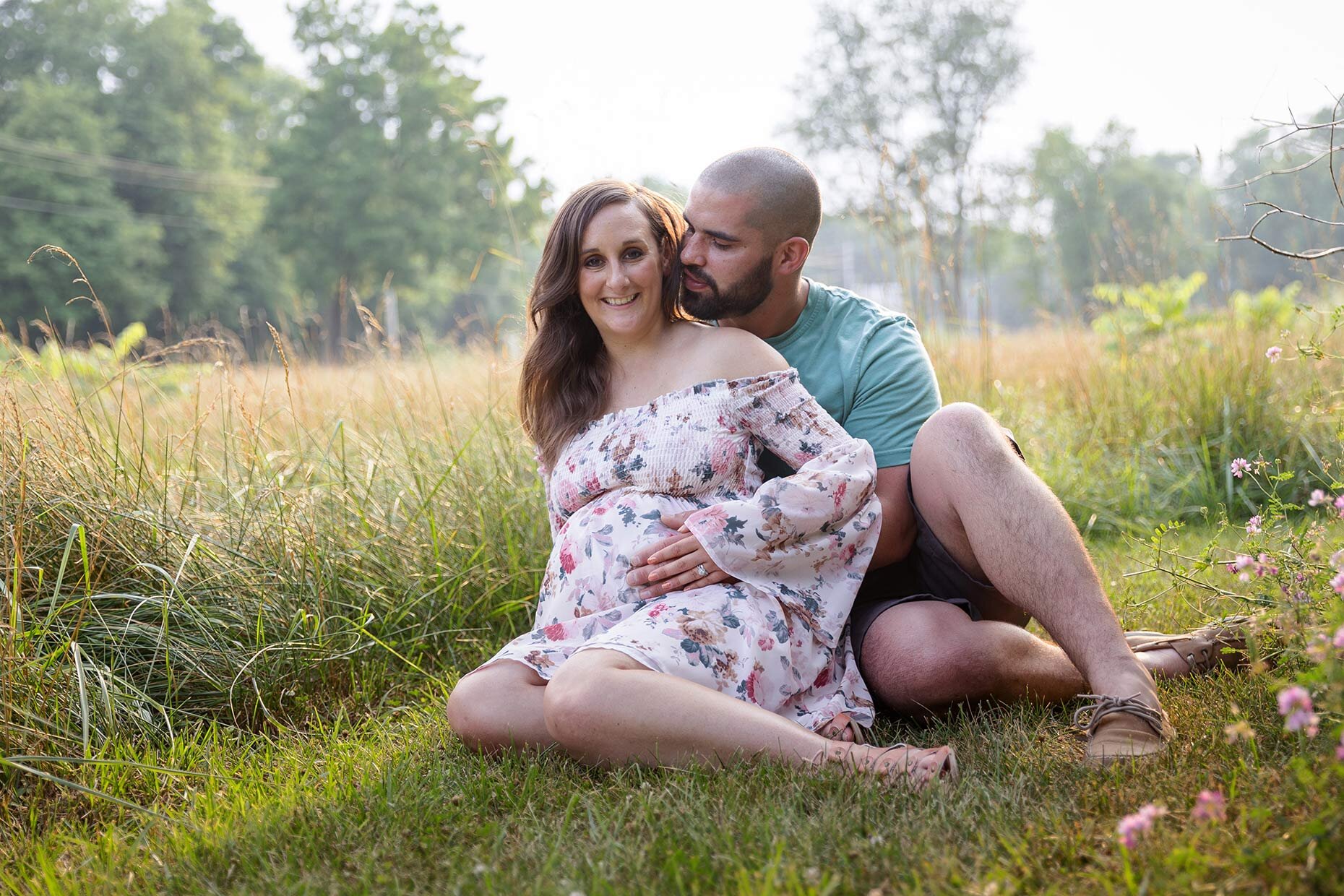 Seated Maternity Photo in grassy field at sunset