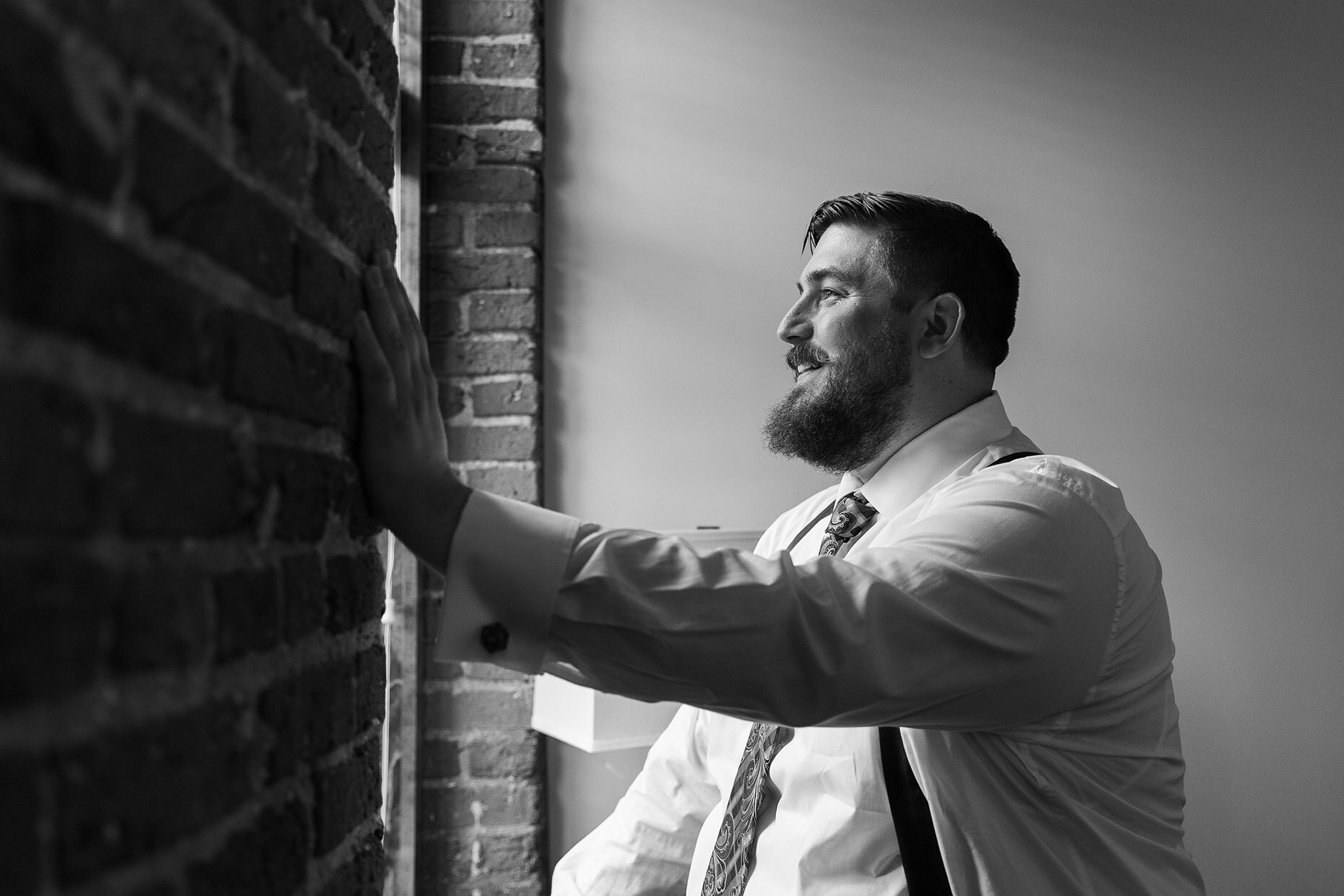 Groom looking out a window in black and white