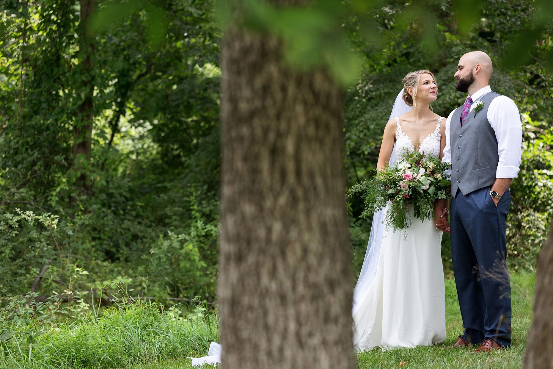 Bride and Groom caught looking at each other from behind a tree