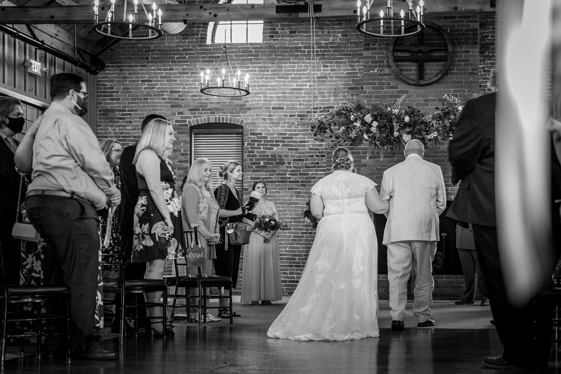 Wedding Ceremony processional in black and white of back of dress and train
