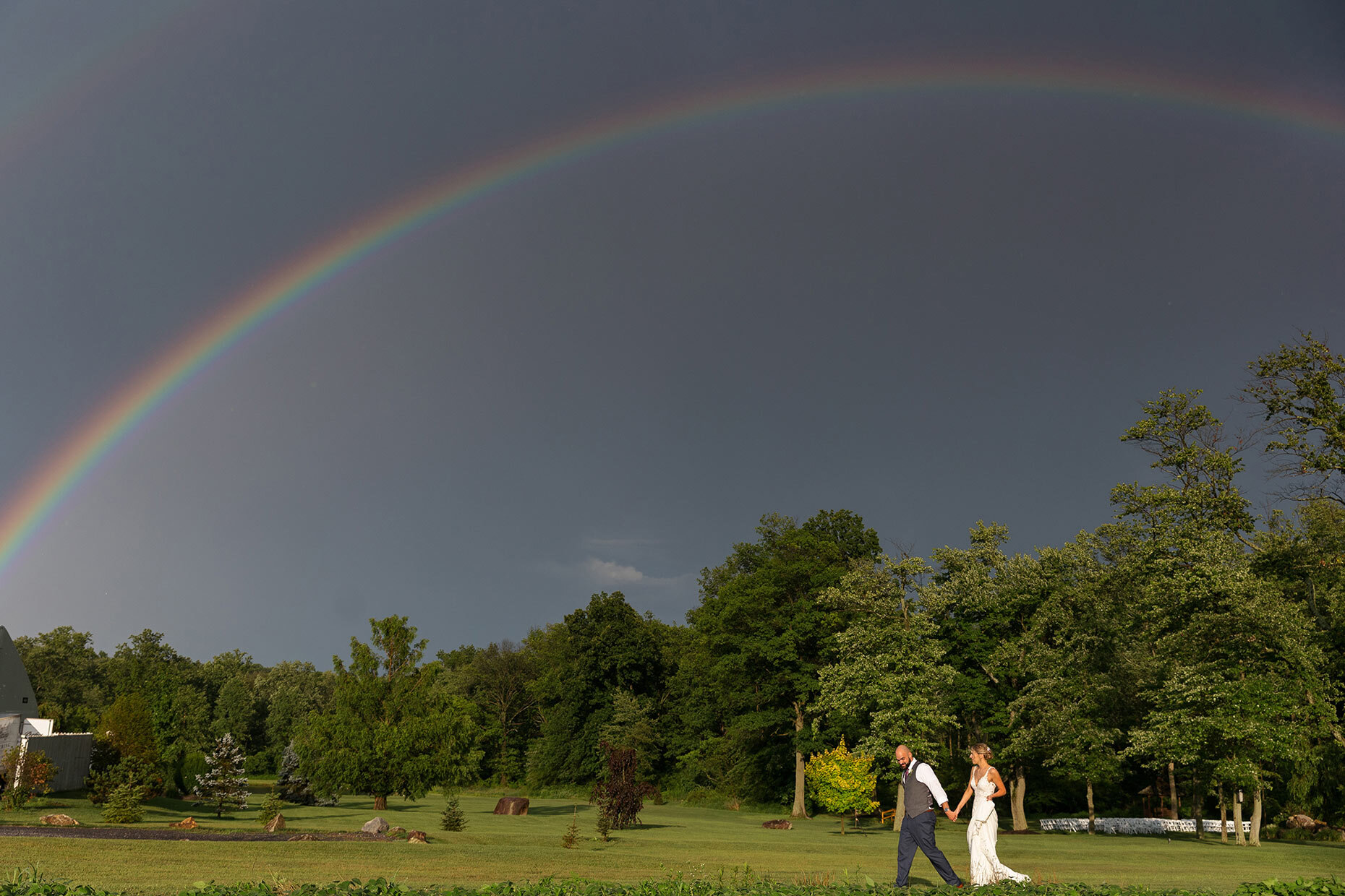 Bride &amp; Groom walking under a rainbow