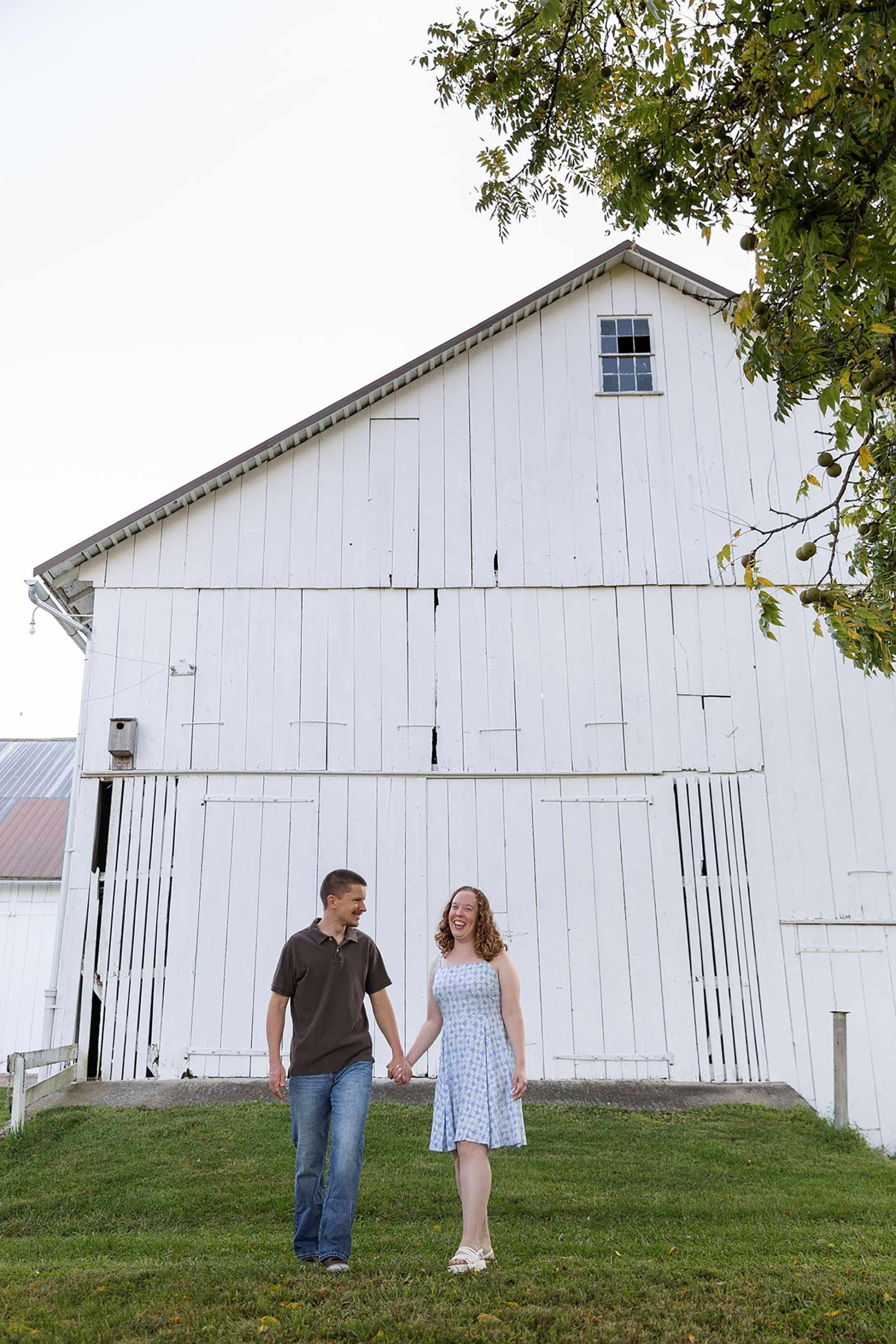 Walking and laughing in front of a white barn 