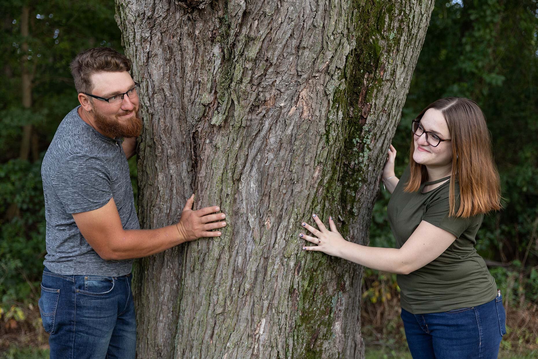 Couple peeking around a tree 