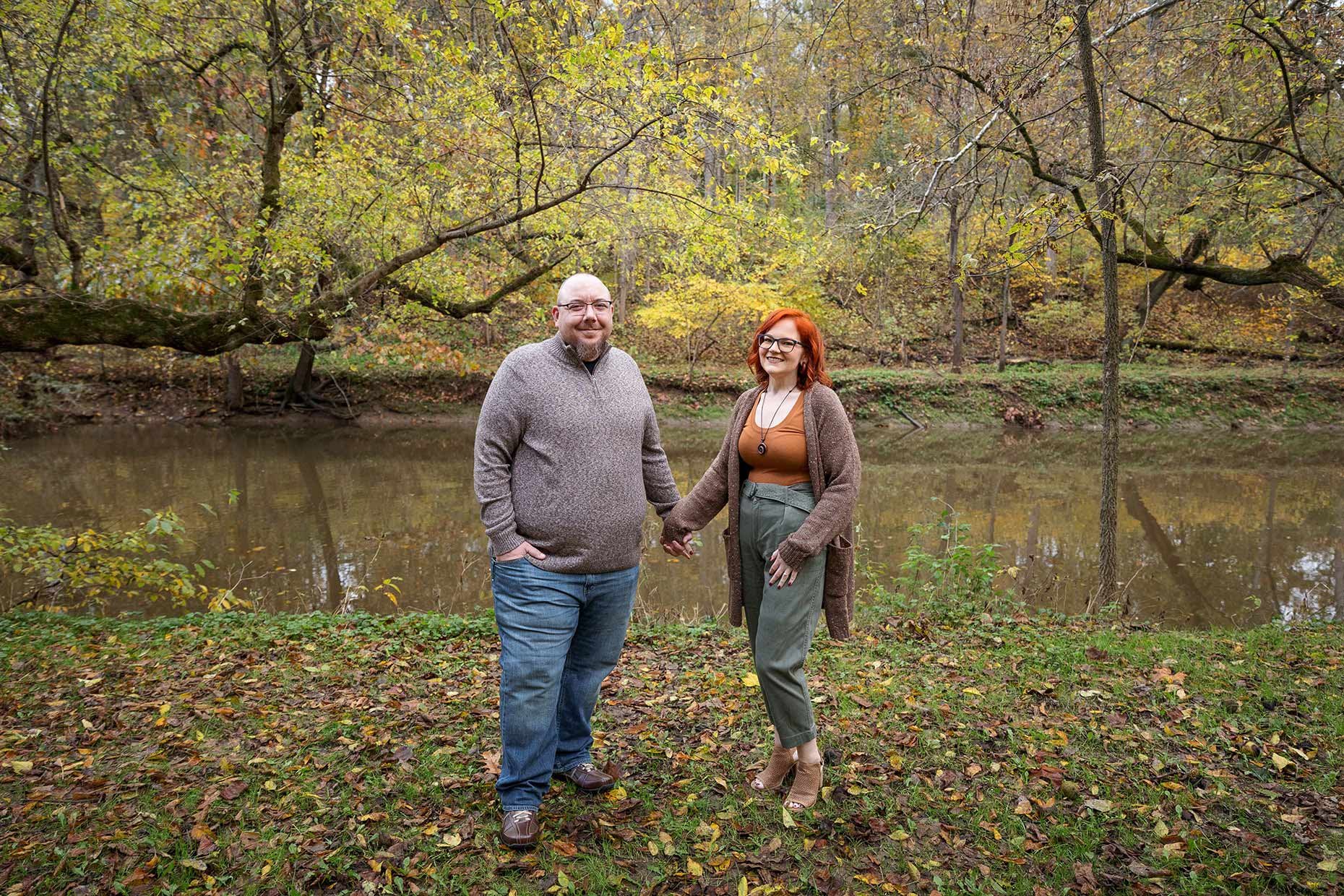 Engaged couple standing in front of a creek