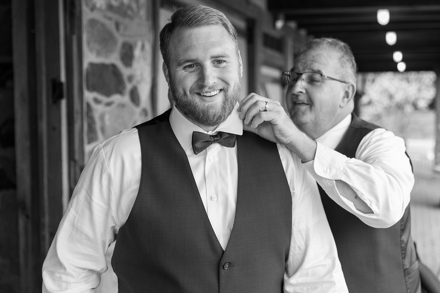 Black and white of dad adjusting groom's bow tie