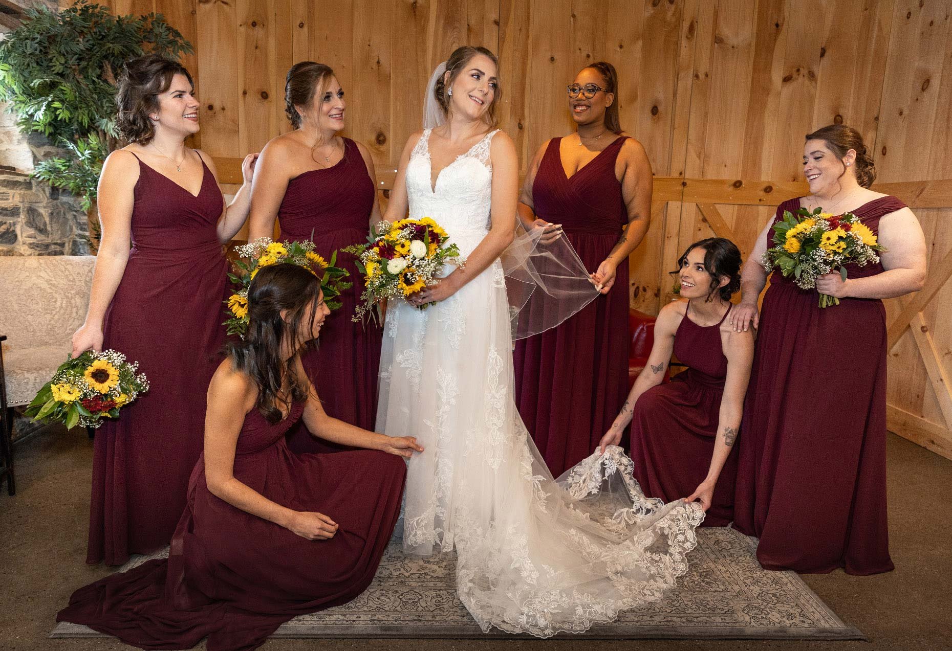 Bridesmaids in Maroon adjusting bride's dress