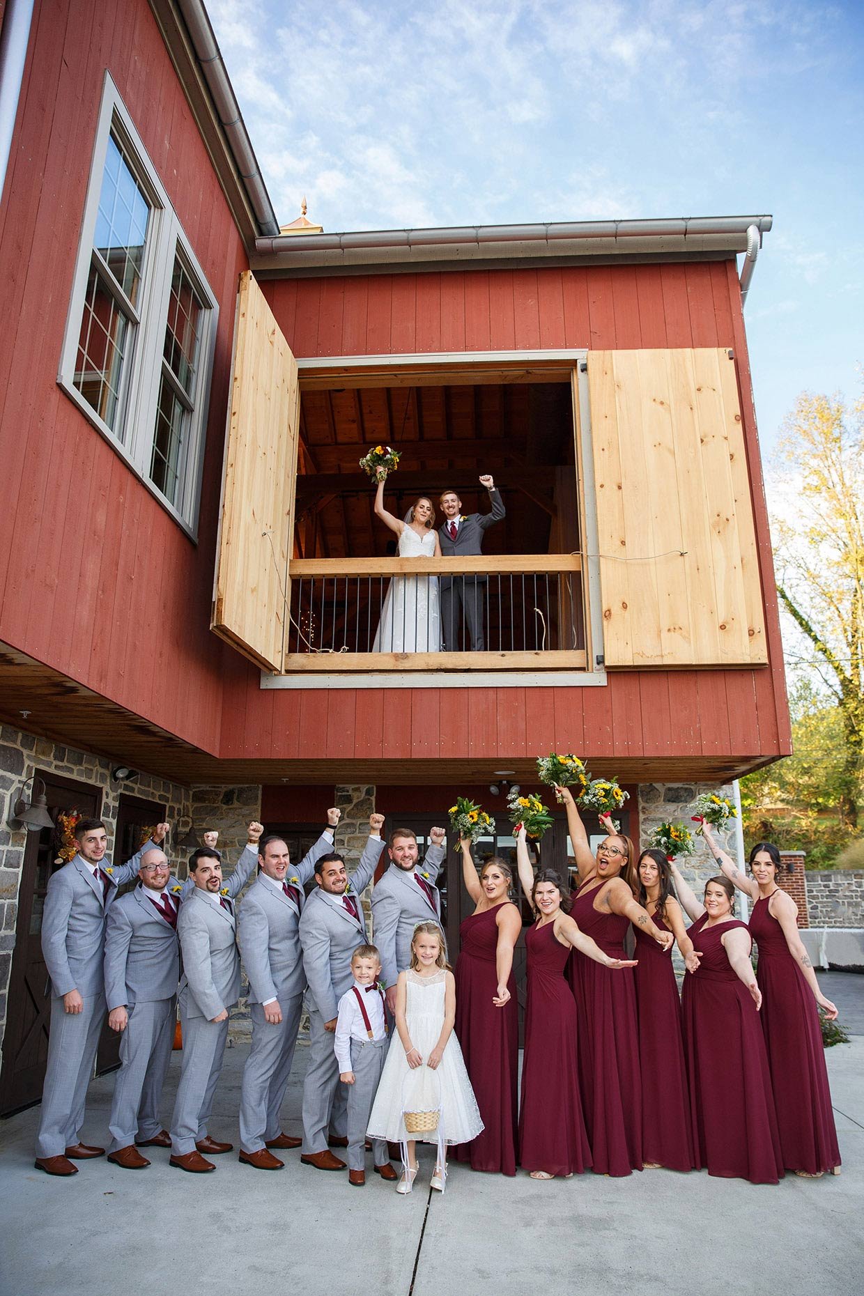 Bridal party celebrates bride and groom in front of barn