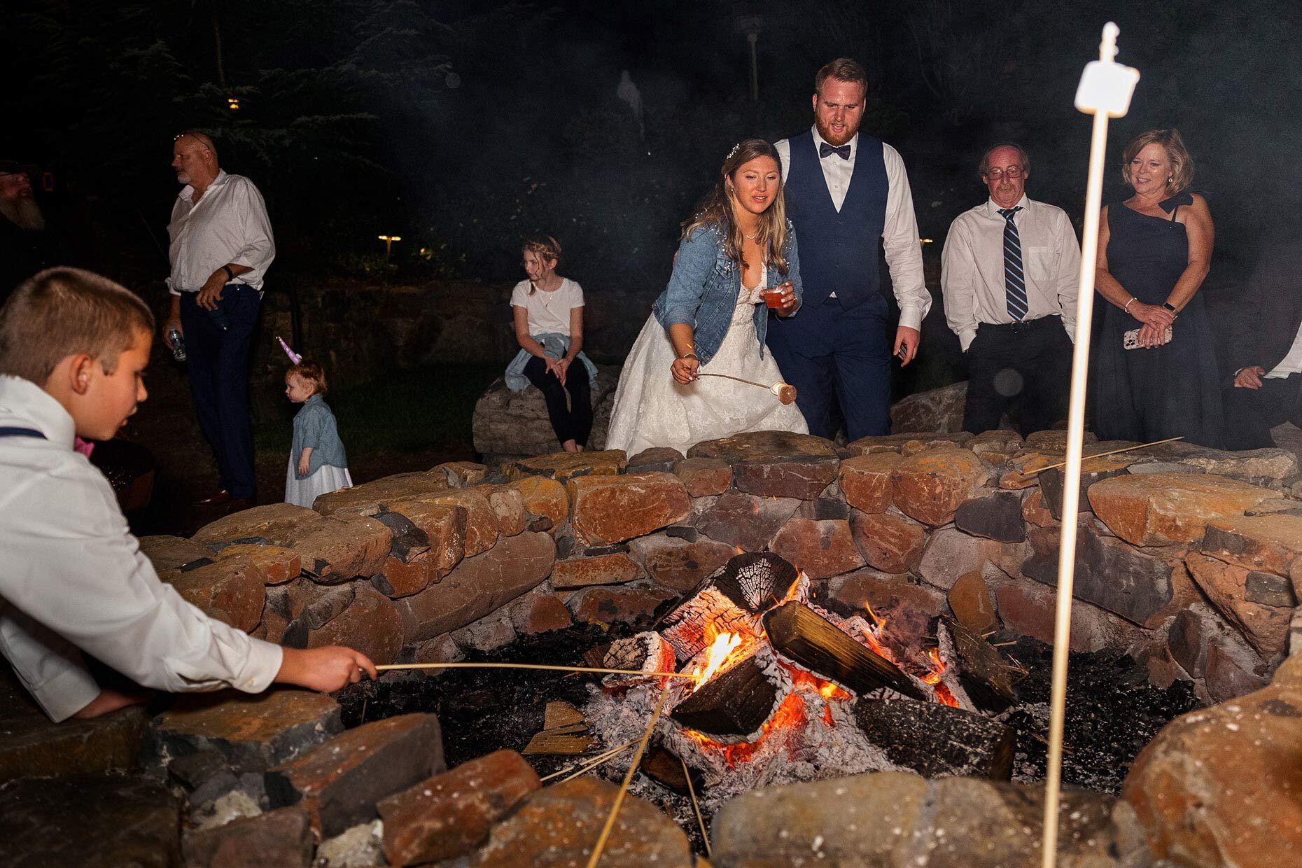 Bride roasting marshmellow at firepit at reception 