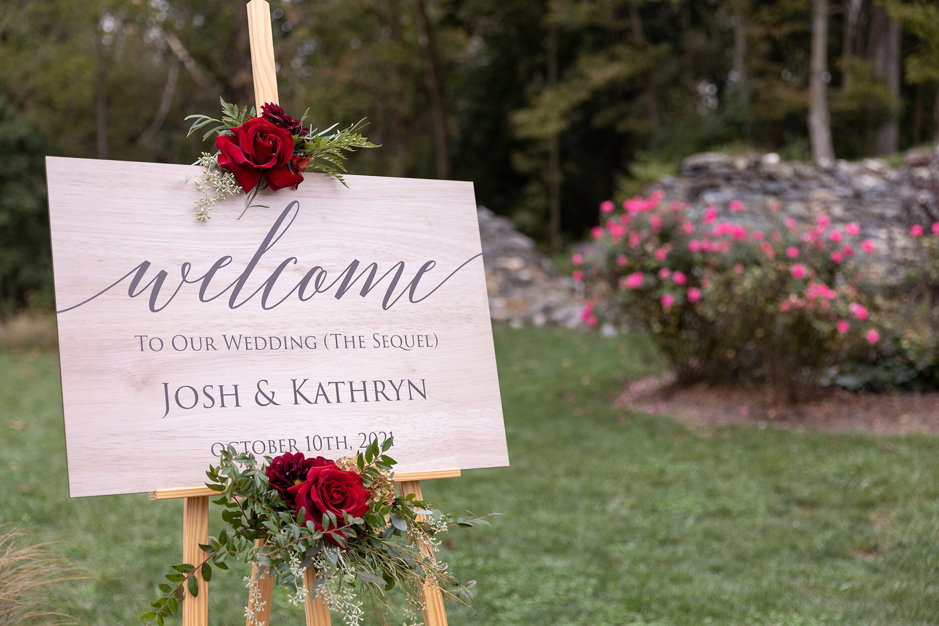 Welcome sign with pink flowers at outdoor wedding