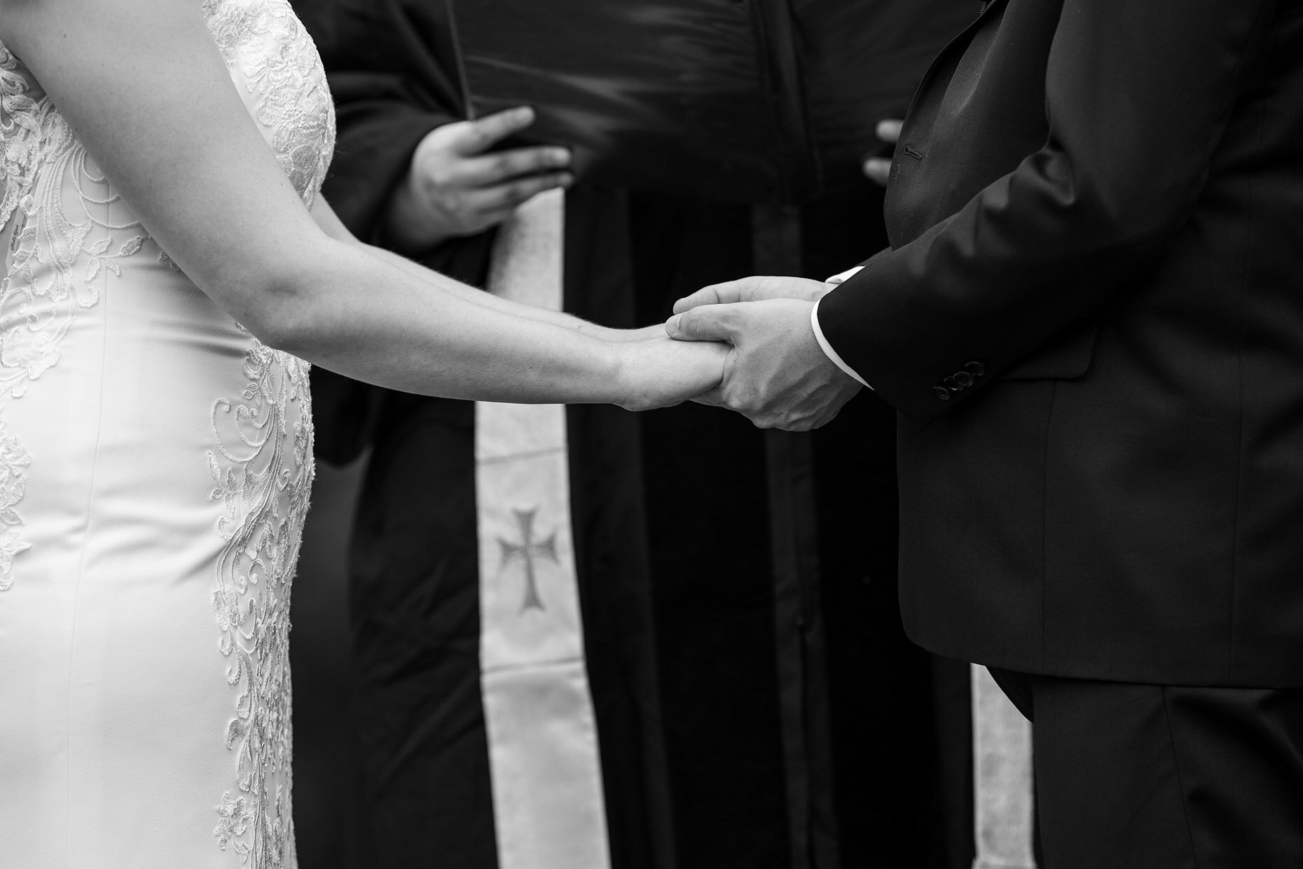 Black and white close up of bride and groom holding hands