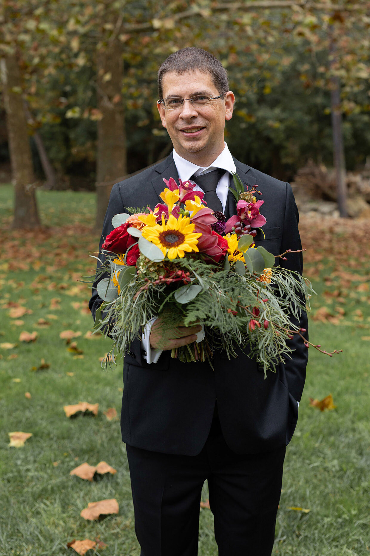 Groom holding bouquet of sunflowers for bride