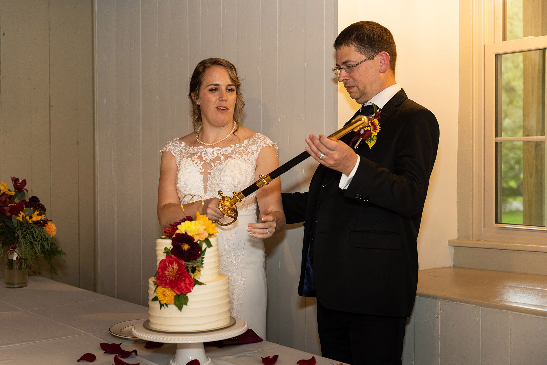 Bride &amp; Groom cut wedding cake with sword