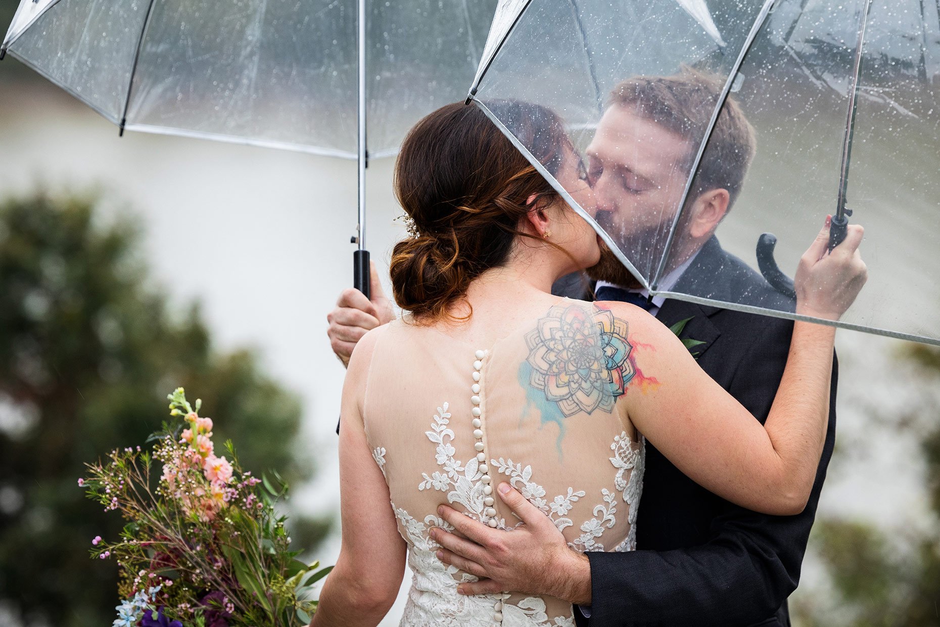 Bride and Groom kissing in the rain under umbrellas