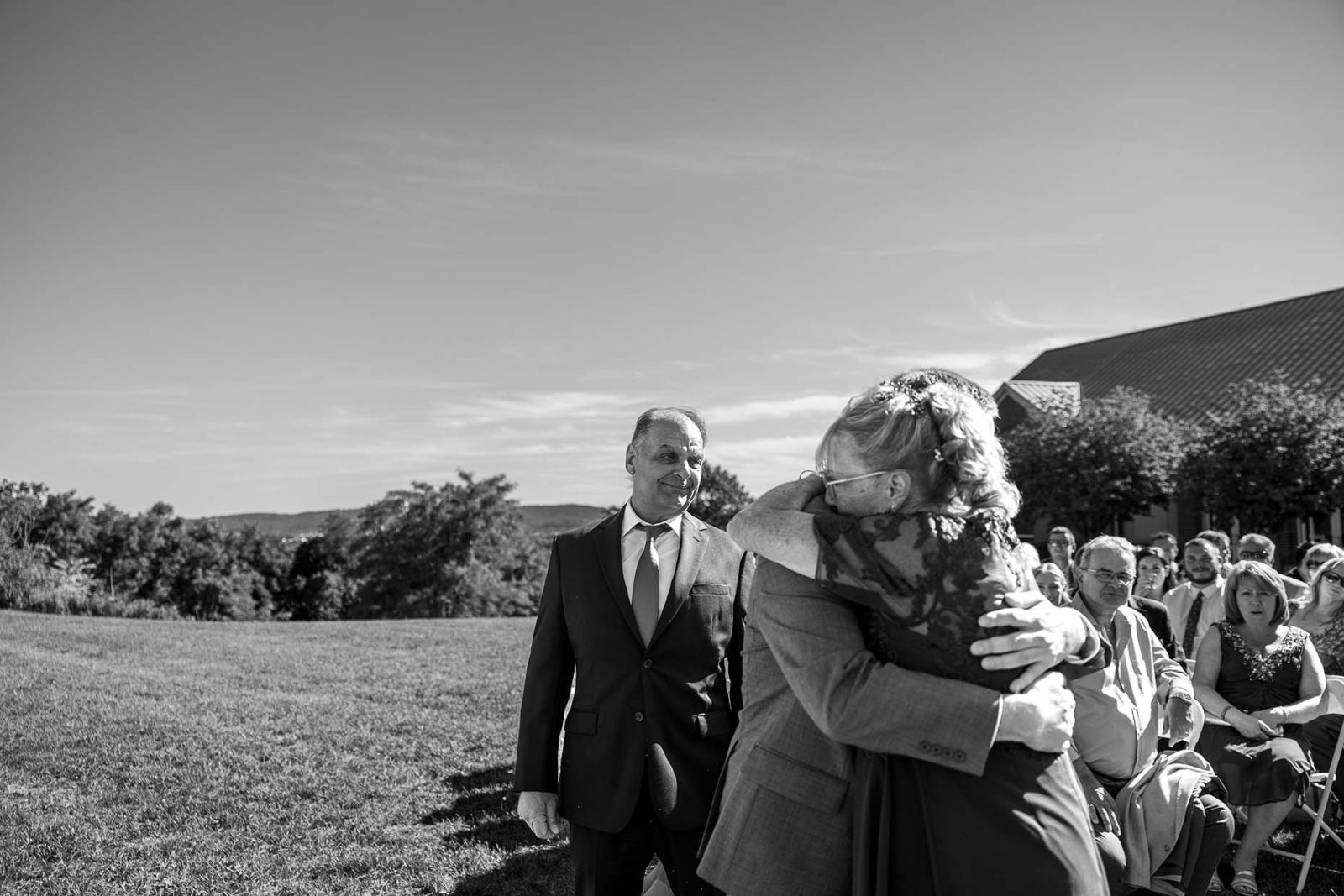 Father of the Groom Watching Son Hug Mother